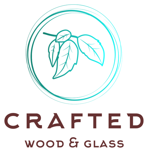 A logo-style graphic with a teal circular outline and leaf illustration above the words 'CRAFTED WOOD & GLASS' in dark brown lettering on a white background.