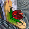 A stained glass tulip light shaped like a flip-flop sandal, resting on a stack of books on a black metal patio chair.