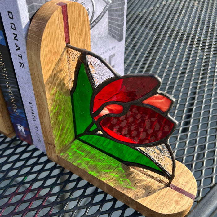 A stained glass tulip light shaped like a flip-flop sandal, resting on a stack of books on a black metal patio chair.