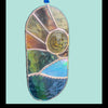 A stained glass suncatcher with a sunburst design, featuring a central circular window and multiple geometric panels in gold, green, blue, and brown tones, suspended by a blue ribbon.