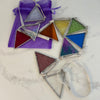 A set of triangular stained glass window bunting with silver metal frames, shown on a white marble surface next to a purple organza bag.