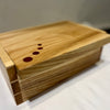 A rectangular wooden box with a hinged lid, made of light natural wood with three small circular cutouts on the lid, resting on a white surface.