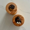 Two round wooden keepsake boxes with circular lids, each featuring a polished inlay of a fossilized ammonite shell, displayed on a light marble surface.